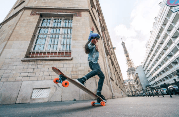 Femme qui fait une figure acrobatique sur une planche de skate dans les rues de Paris