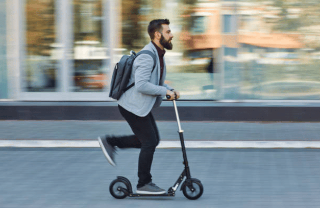 Homme avec un sac à dos sur une trottinette