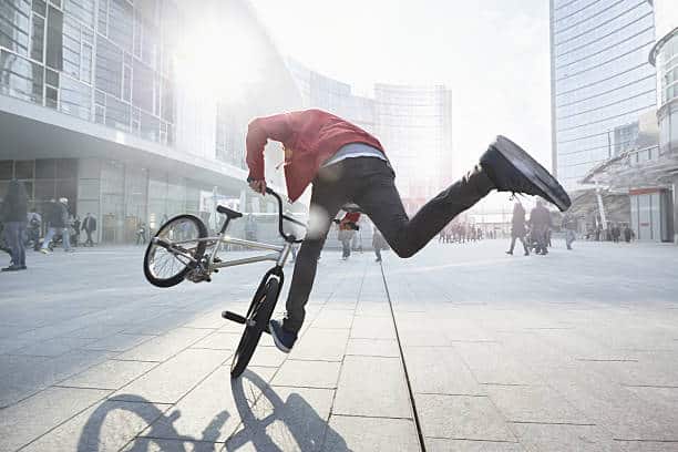 Homme qui fait une figure acrobatique sur un vélo BMX en pleine ville